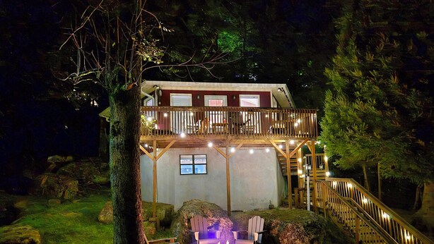 A two-story wooden cabin with a balcony, a fire pit, and a staircase leading to the upper level. - New Kitchen! ‖ Hot Tub coming August 7th! ‖ 2 Mins to Slopes ‖ Paved Road Access (Beech Mountain)