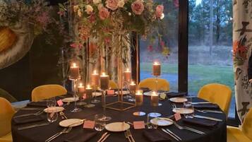 A round dining table set with yellow chairs, candles, and a floral centerpiece.