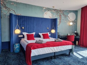 A modern hotel room with a large bed, red and white bedding, blue curtains, and a decorative wall with a tree design. - Ego Spa Adult Only (Birstonas)