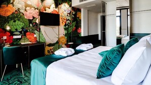 A hotel room with a bed, green pillows, a desk with a chair, and a wall with a floral mural. - Ego Spa Adult Only (Birstonas)