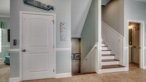 A hallway with a white door, a staircase, and a light blue wall.