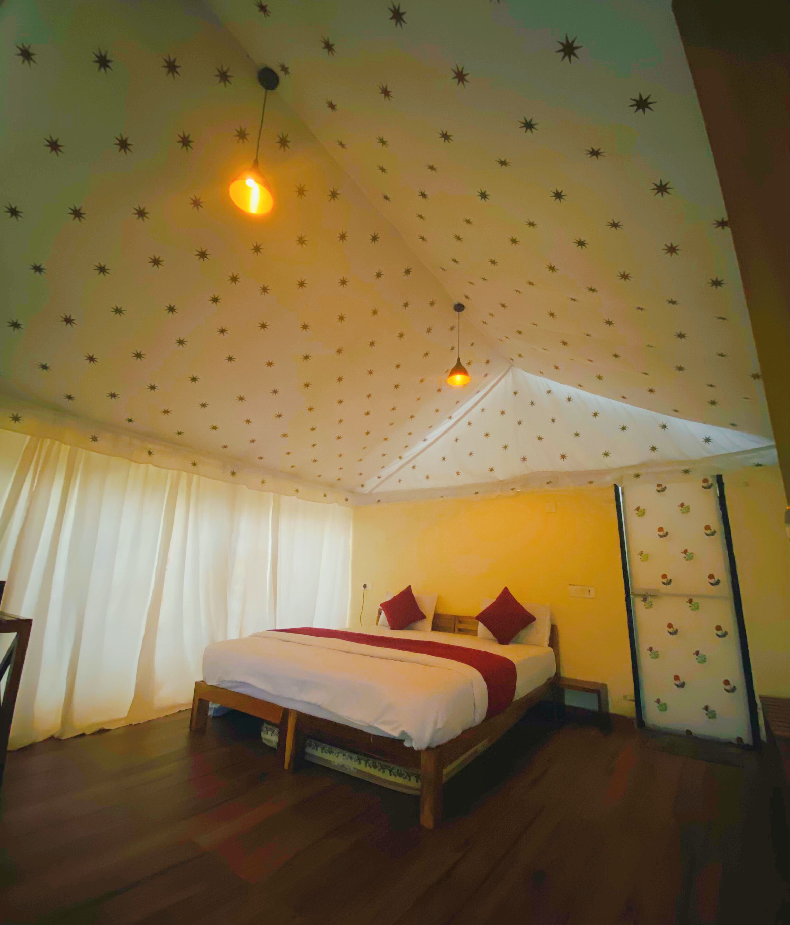 A bedroom with a bed, curtains, a nightstand, and a wall with star patterns.