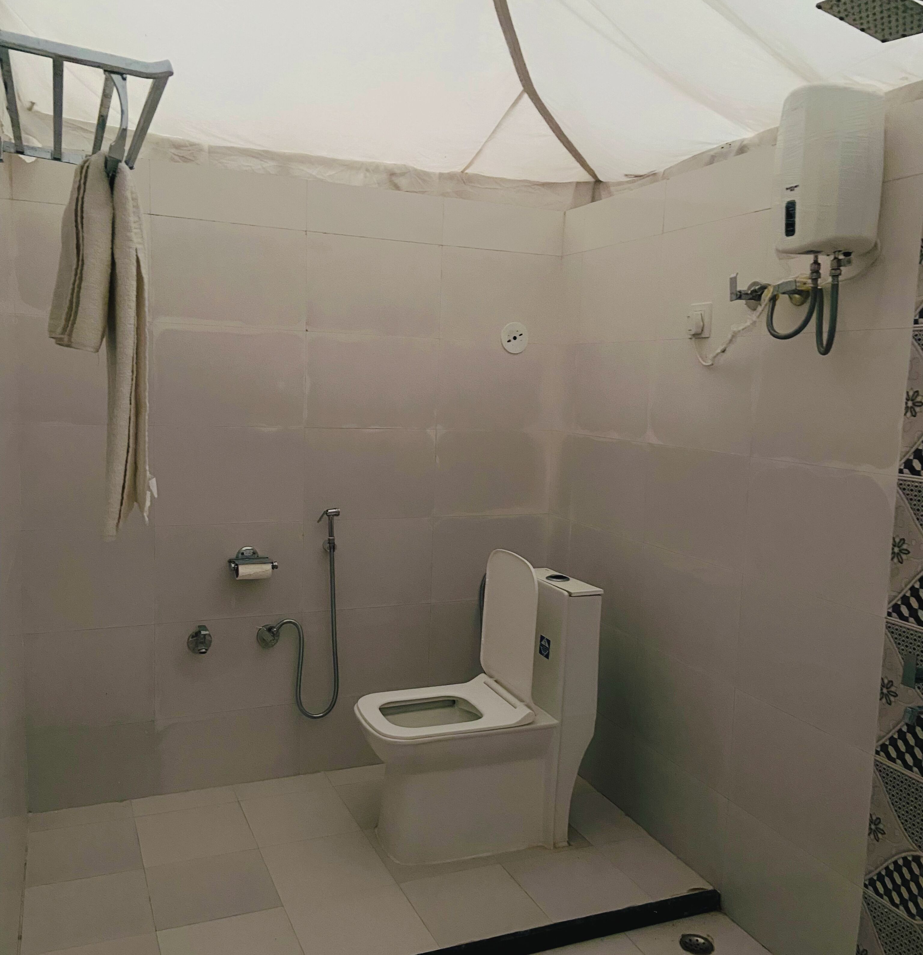 Ein kleines Badezimmer mit Fliesen, einer Toilette, einer Dusche und einem Handtuchhalter.