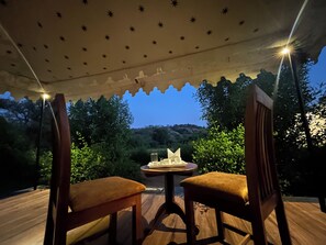 An outdoor seating area with two wooden chairs and a small table, under a canopy with star patterns. - Jawai Horizon Camp (Bali)