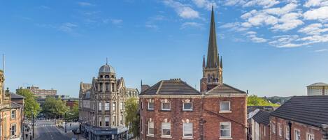 A historic building with a prominent tower and a dome, situated in a city street with adjacent brick buildings.