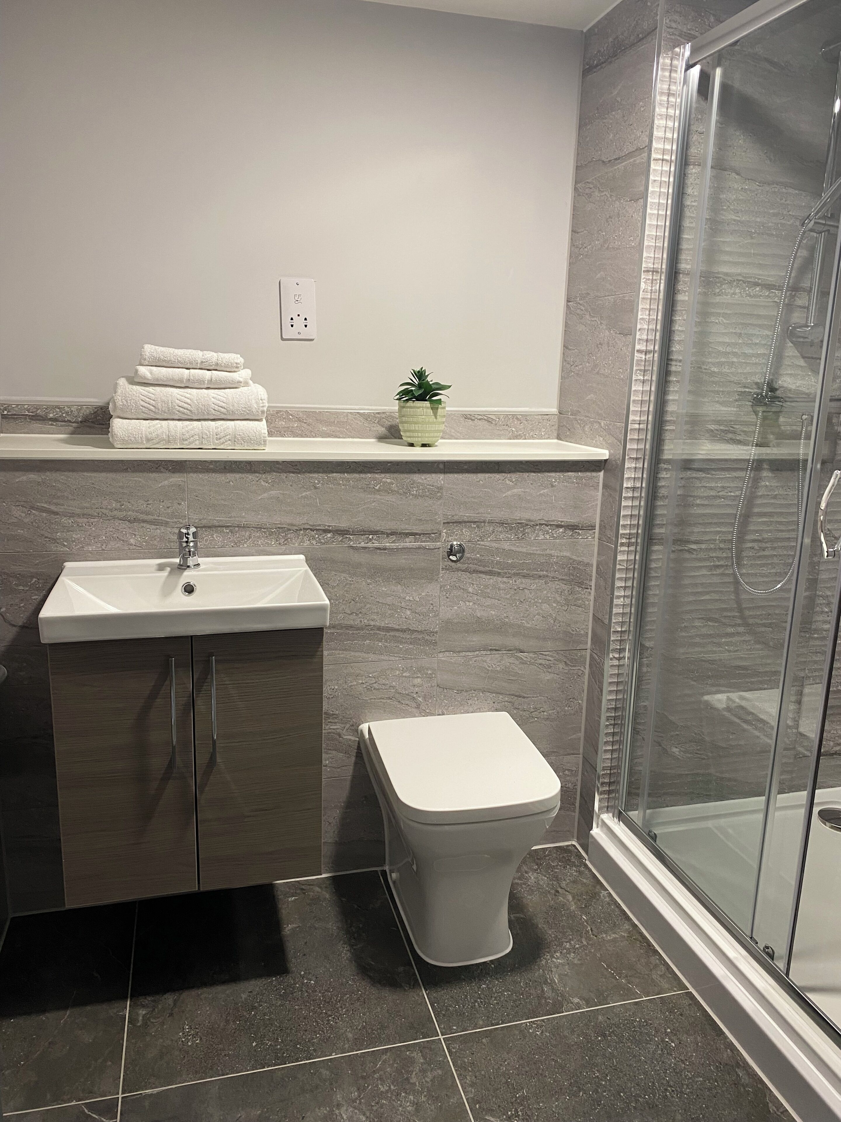 Une salle de bain moderne avec un lavabo, des toilettes et une douche à parois de verre.