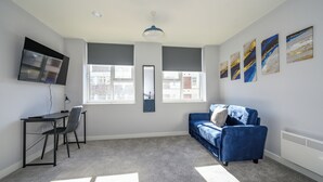 A modern room with a desk, chair, blue sofa, and artwork on the walls. - Marygate by Deuce Hotels Ltd (Wakefield)