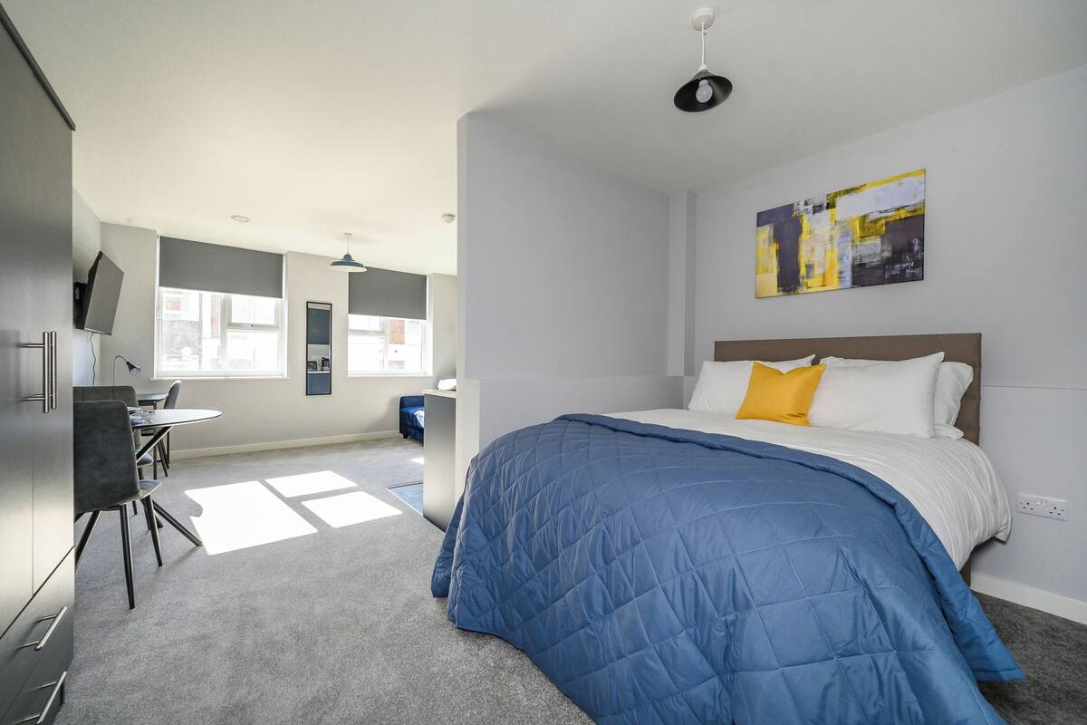 A modern bedroom with a large bed, a desk, and a chair.