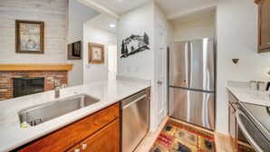 A modern kitchen with stainless steel appliances, wooden cabinets, and a marble countertop.