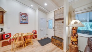 A cozy room with a wooden dining table, two chairs, a bear-shaped lamp, and a door with frosted glass.