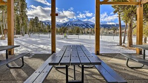 A wooden pavilion with picnic tables, a snow-covered ground, and a mountain view.