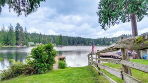 A lakeside property with a wooden deck, a flag, and a view of the lake and forest. - Lakefront Snohomish Home ~ 13 Mi to Historic Dtwn (Snohomish)