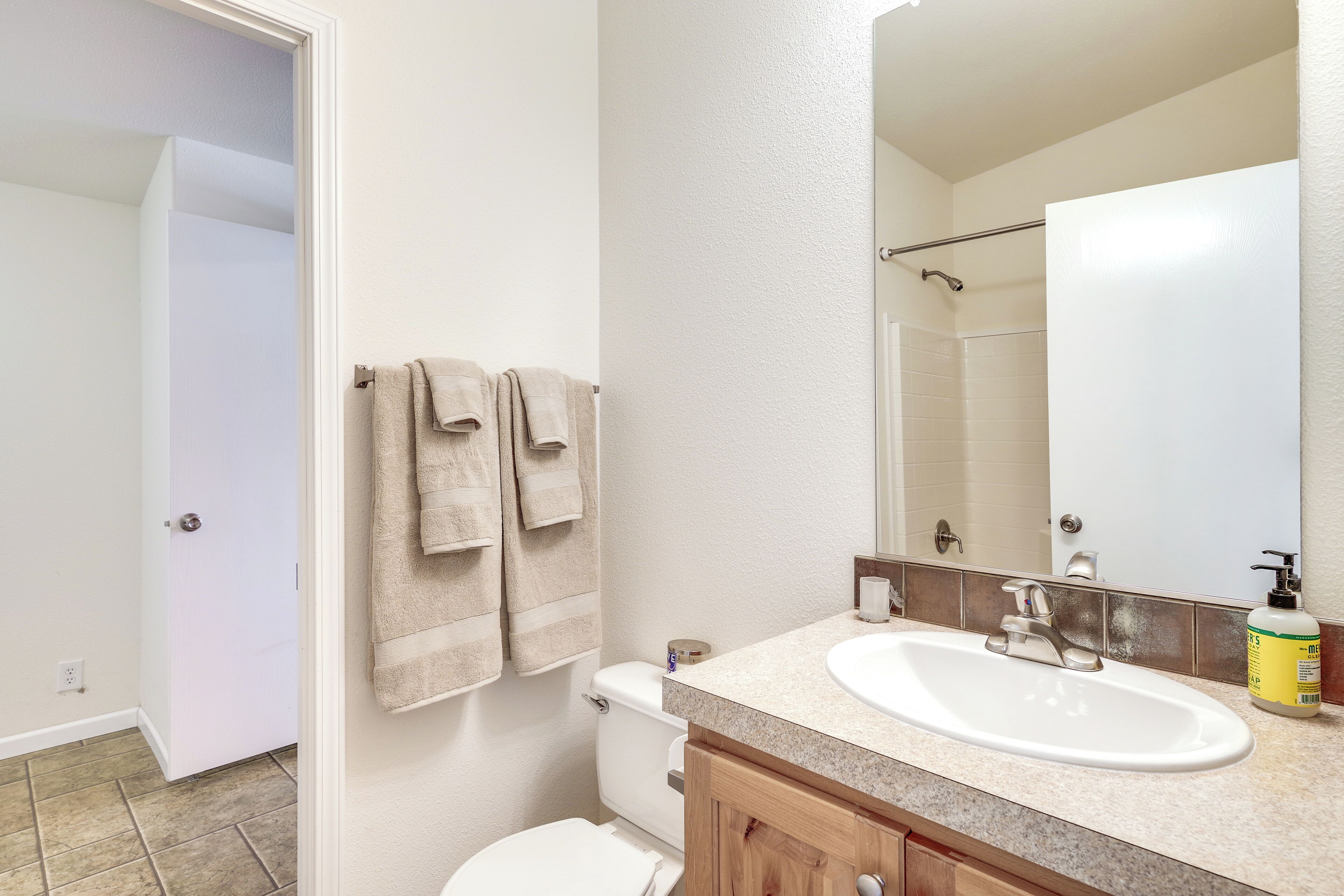 A bathroom with a white sink, beige towels, and a shower area.