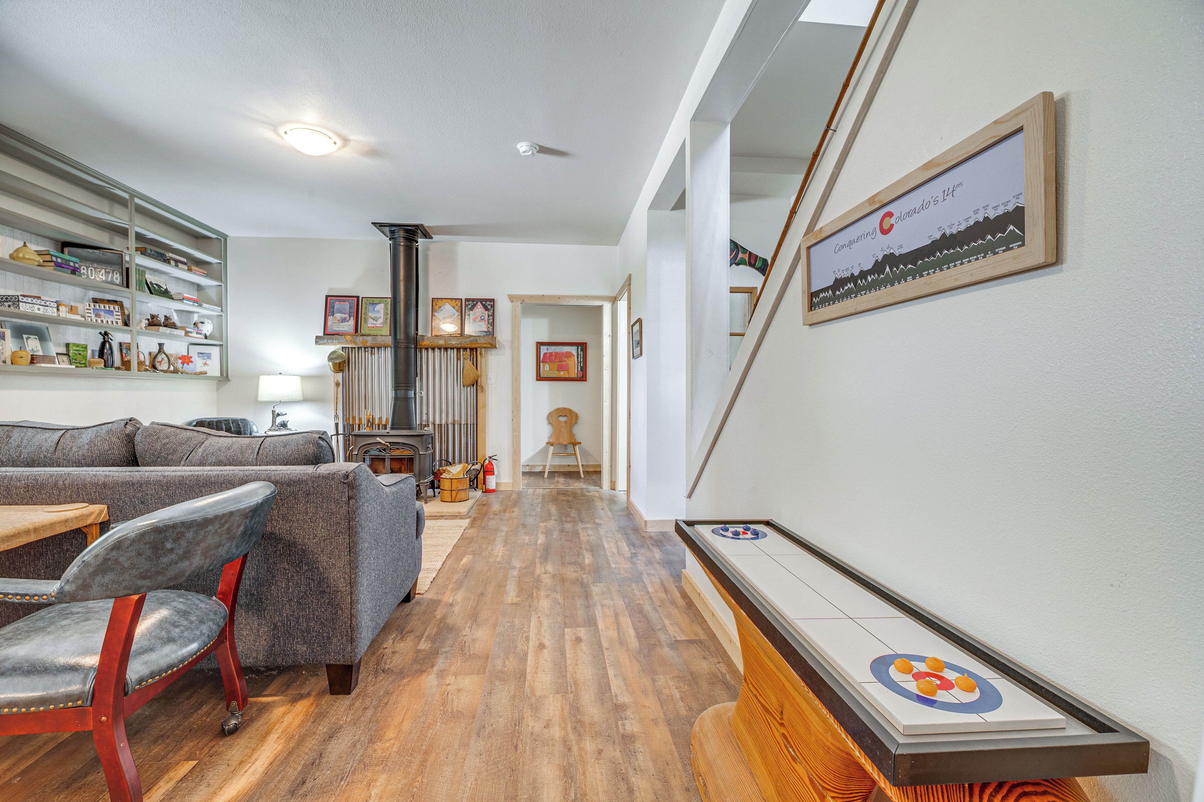 Un salon avec un canapé, des fauteuils, un plancher en bois, une cheminée et un tableau encadré au mur.