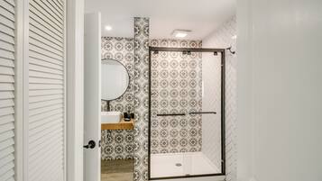 A bathroom with a shower, a sink, and a mirror.