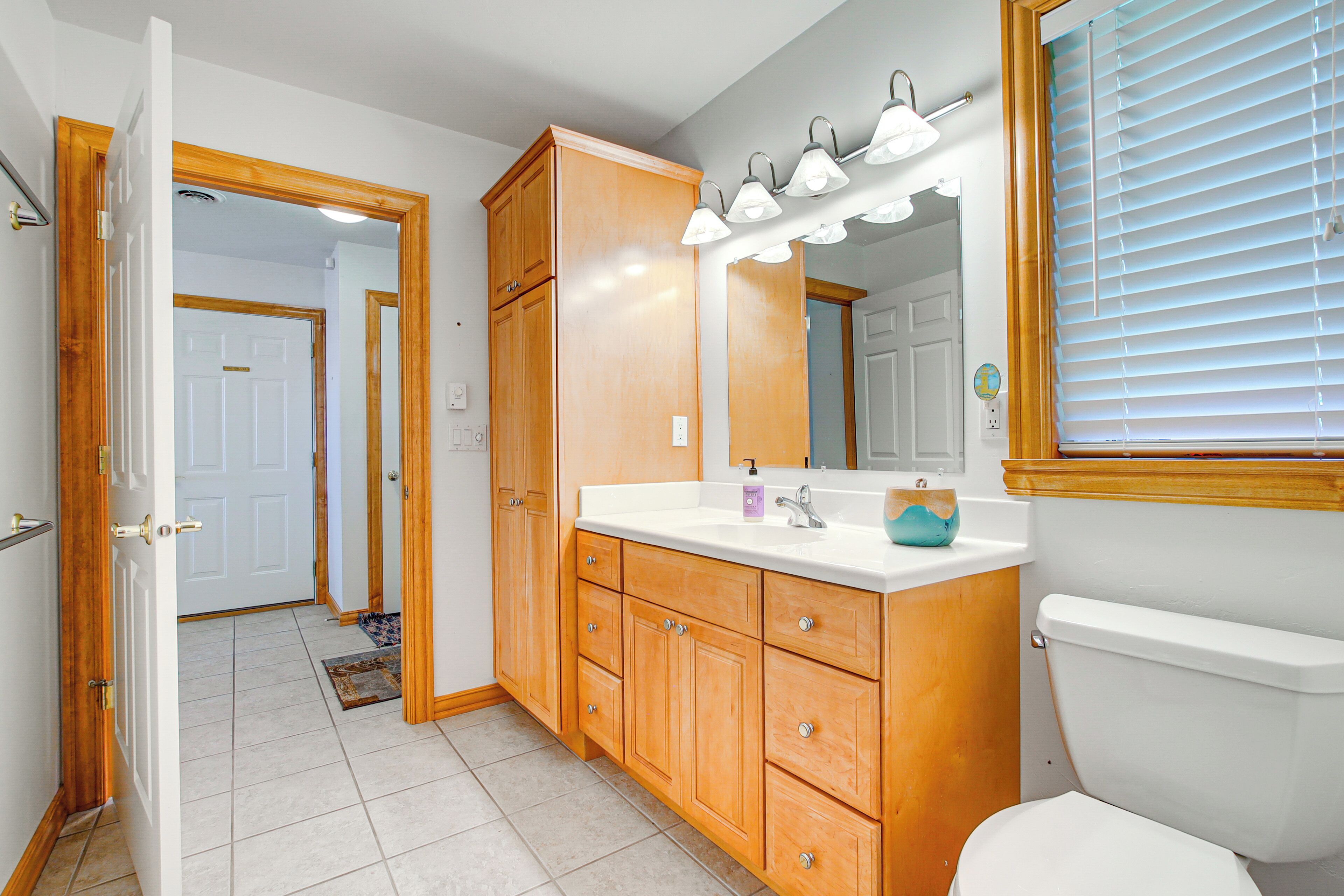 A bathroom with wooden cabinets, a white sink, and a toilet.