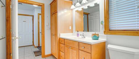 A bathroom with wooden cabinets, a white sink, and a toilet.