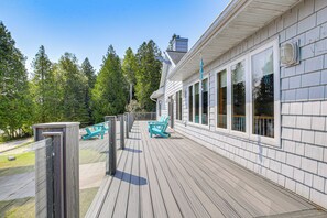 A wooden deck with two turquoise chairs and a table, overlooking a forested area. - Beach Access on Lake Michigan: Sturgeon Bay Home (Sturgeon Bay)
