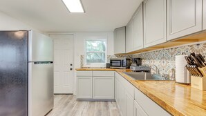 Una cocina moderna con refrigerador, microondas, pileta y encimera de madera.
