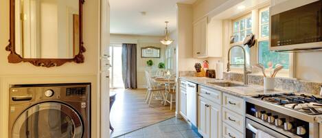 A modern kitchen with a built-in washer, a large mirror, and a dining area with a chandelier.