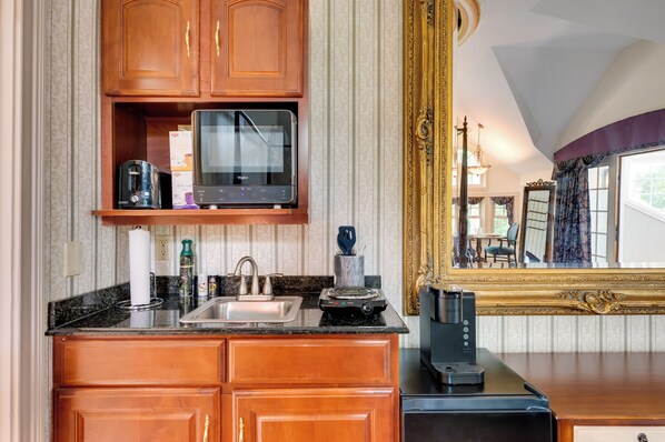 A kitchen with wooden cabinets, a built-in microwave, a coffee maker, and a large mirror with a gold frame. - Mountain Views: Beautiful Nestlenook Farm Home! (Jackson)