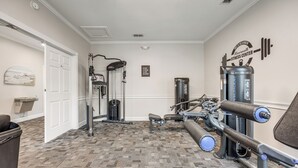 Un gimnasio con diversos equipos de ejercicio, un cartel en la pared y una alfombra estampada.