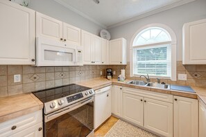 Una cocina moderna con armarios blancos, microondas integrado, estufa y lavavajillas.