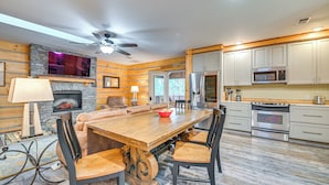 A modern kitchen with a large island, built-in appliances, and a stone fireplace. - Tree Tops Retreat ~ 19 Mi to Lake George! (Chestertown)