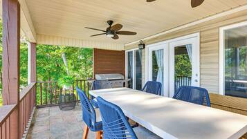 Une terrasse couverte avec une table et des chaises, un ventilateur de plafond et un barbecue.