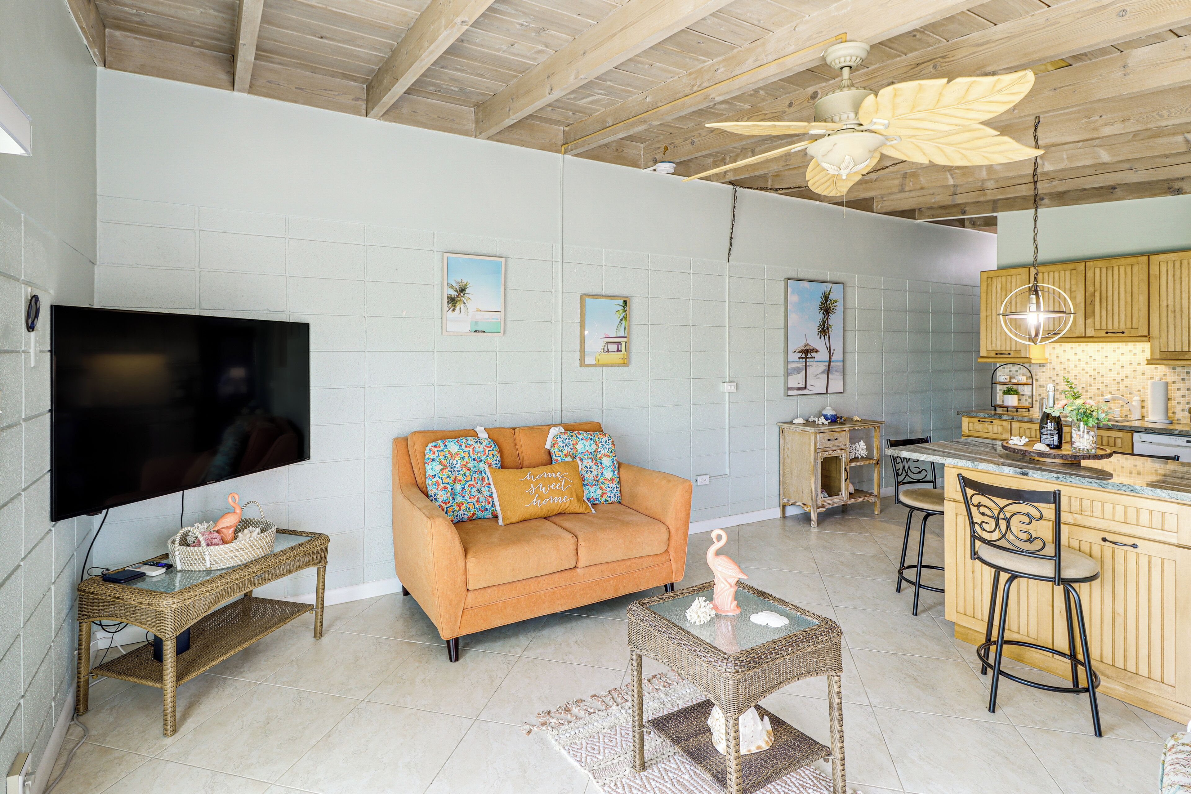 A living room with a sofa, TV, and a kitchen area with bar stools.