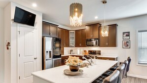 A modern kitchen with a central island, stainless steel appliances, and a dining area with bar stools. - Home ~ 3 Mi to Penn State: Pets Welcome! (State College)