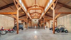 A spacious indoor area with a high ceiling, wooden beams, and a polished concrete floor. - Above Nashville Rustic Retreat Farm I 200 Acre Farm | Pool&Spa I Services (Charlotte)