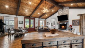 A spacious living area with a wooden ceiling, a large wooden dining table, and a fireplace. - Above Nashville Rustic Retreat Farm I 200 Acre Farm | Pool&Spa I Services (Charlotte)
