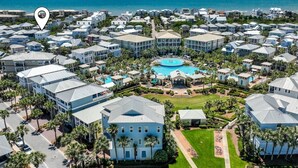 A resort with multiple buildings, a central pool, and a view of the ocean.