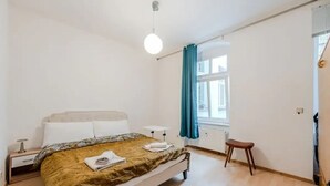 Un dormitorio con cama, mesita de noche y ventana con cortinas.