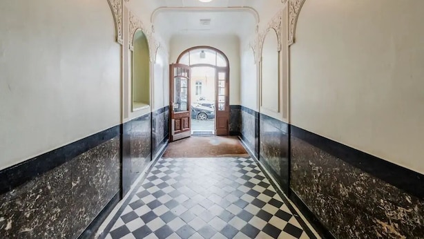 Un pasillo con piso a cuadros, paredes blancas y bordes de mármol negro.