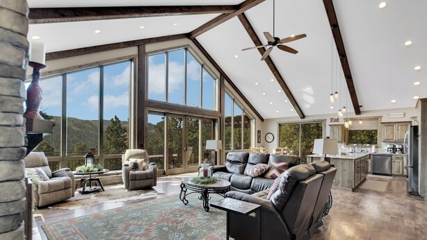 A spacious living area with large windows, a ceiling fan, and a kitchen area. - Aspen Valley, Deadwood SD (Sturgis)
