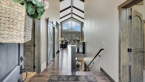 A spacious hallway with a high ceiling, wooden floors, and a staircase leading to a second floor. - Aspen Valley, Deadwood SD (Sturgis)