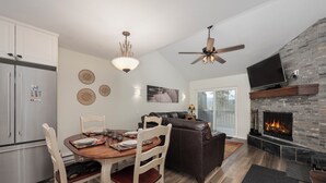 A modern kitchen with a dining area, a fireplace, and a ceiling fan.