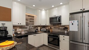 A modern kitchen with white cabinets, stainless steel appliances, a microwave, and a refrigerator.