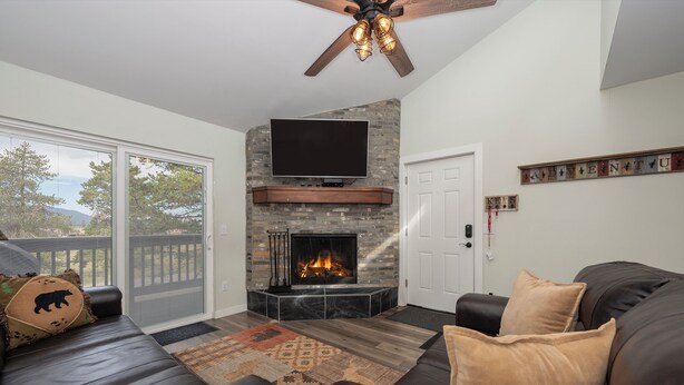 A living room with a fireplace, a television mounted above it, and a ceiling fan.