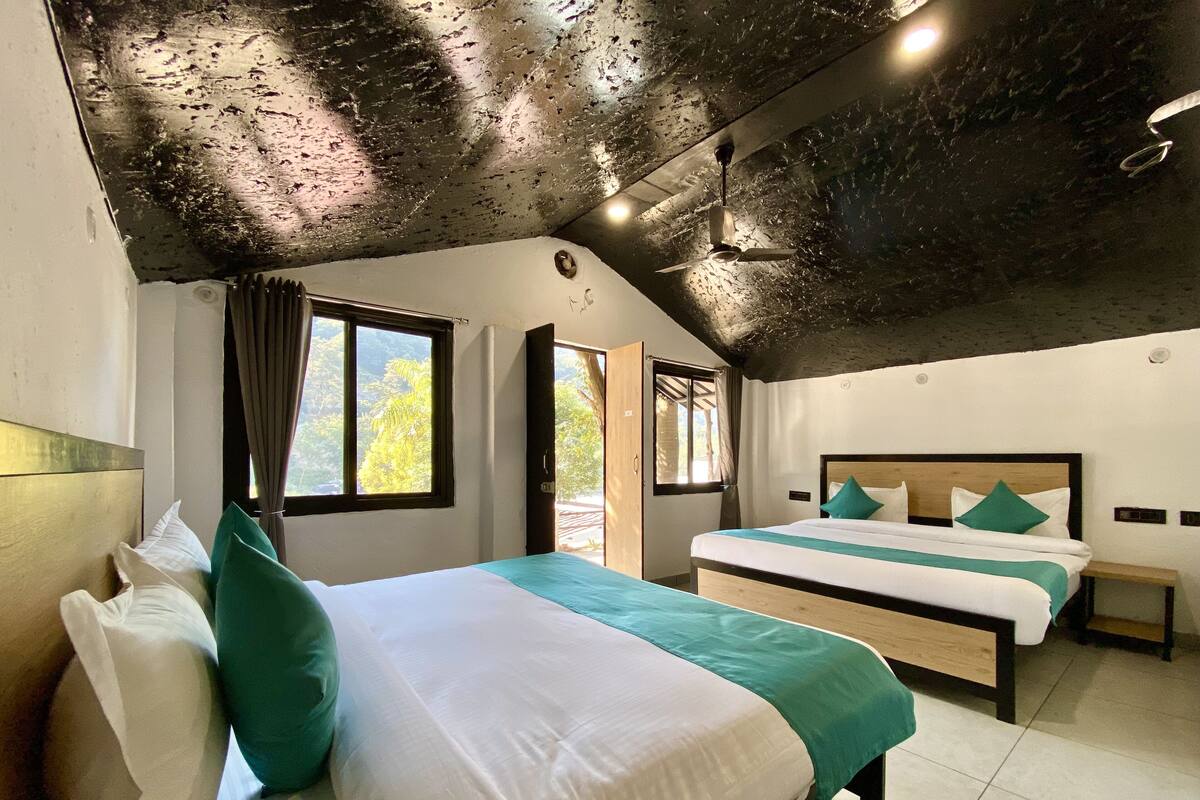 A bedroom with two beds, a ceiling fan, and large windows.