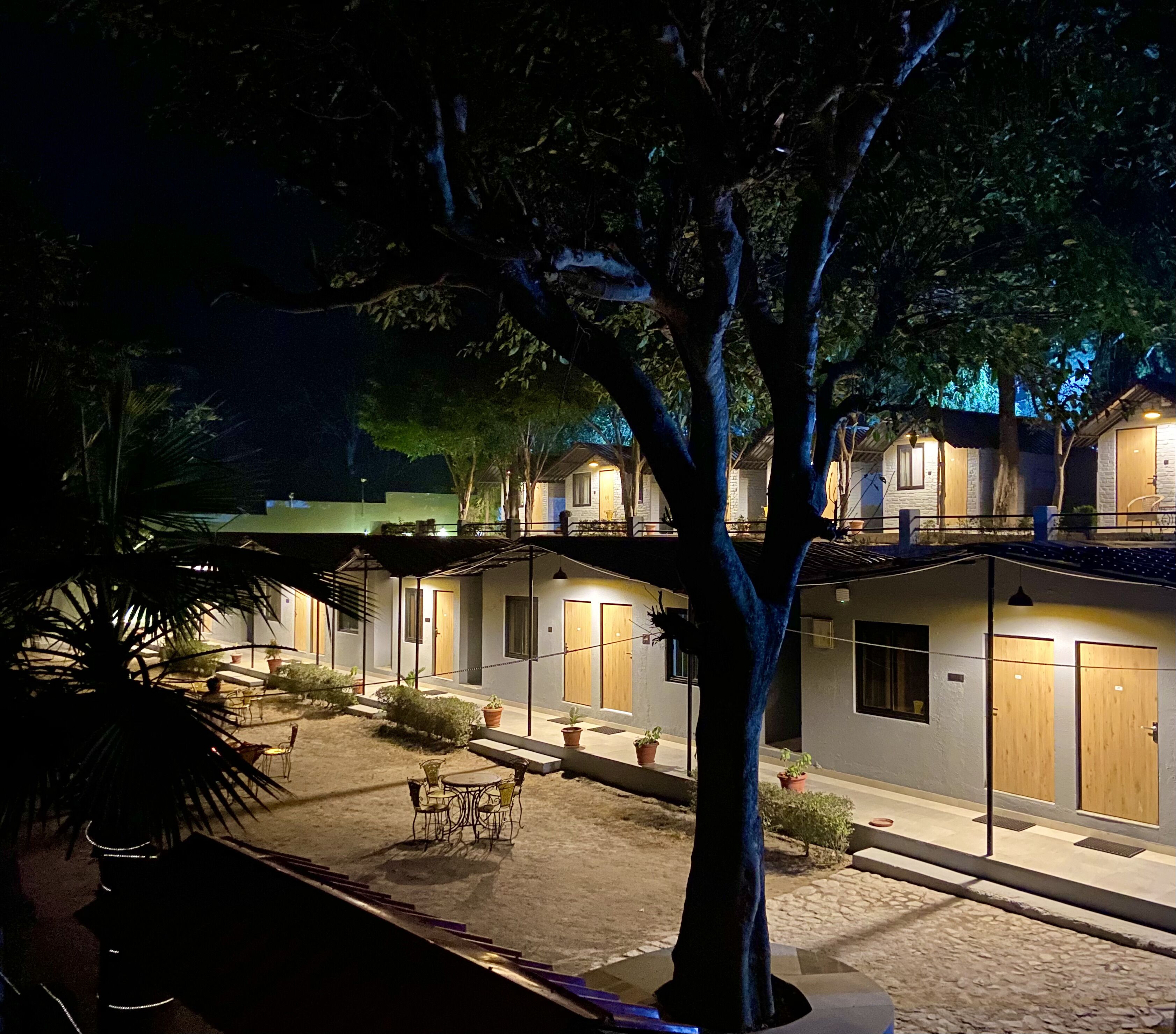 A hotel with multiple rooms, outdoor seating, and a tree in the foreground.