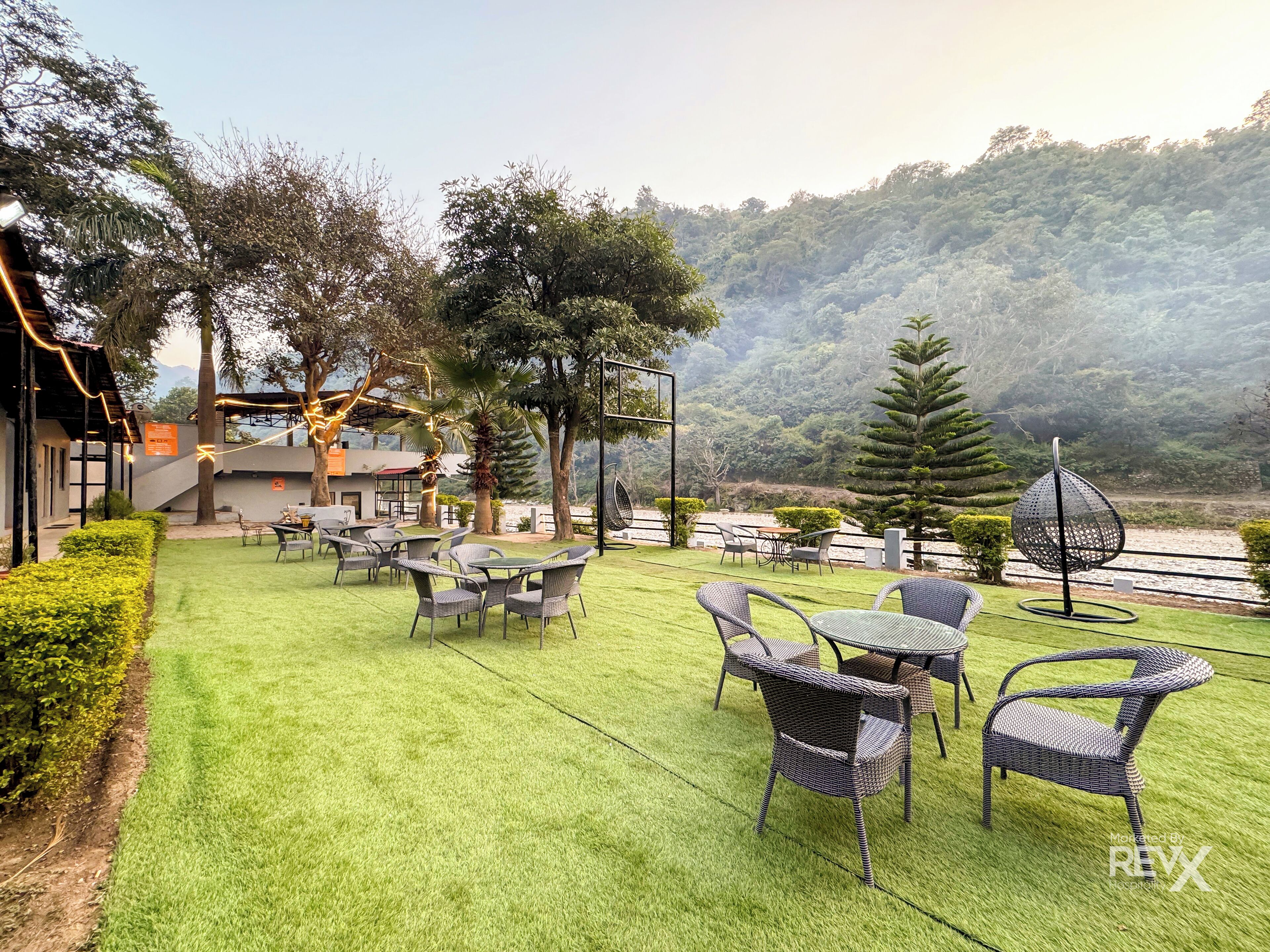 A well-maintained outdoor seating area with wicker furniture and a view of a lush, green hillside.