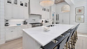 A modern kitchen with white cabinetry, a large island, and a hanging light fixture. - Barefoot By The Sea|Easy Beach Access|Private Pool|Gulf Views from Lookout Tower (Santa Rosa Beach)