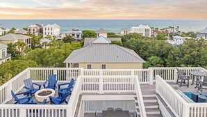 A deck with blue chairs and a fire pit, overlooking a coastal area with houses and a view of the sea. - Barefoot By The Sea|Easy Beach Access|Private Pool|Gulf Views from Lookout Tower (Santa Rosa Beach)