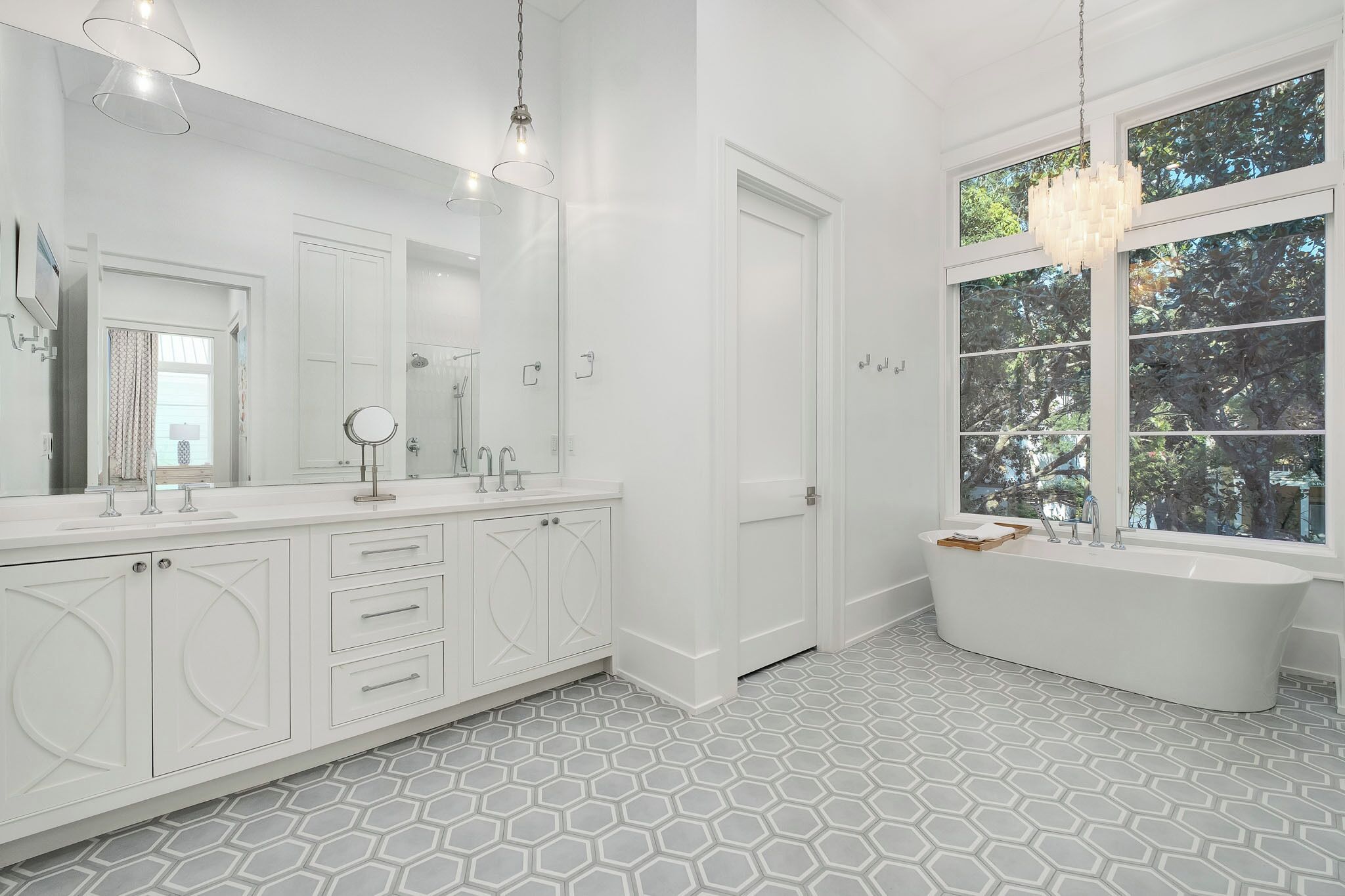 A modern bathroom with a large freestanding bathtub, a double vanity with a mirror, and a large window providing natural light.