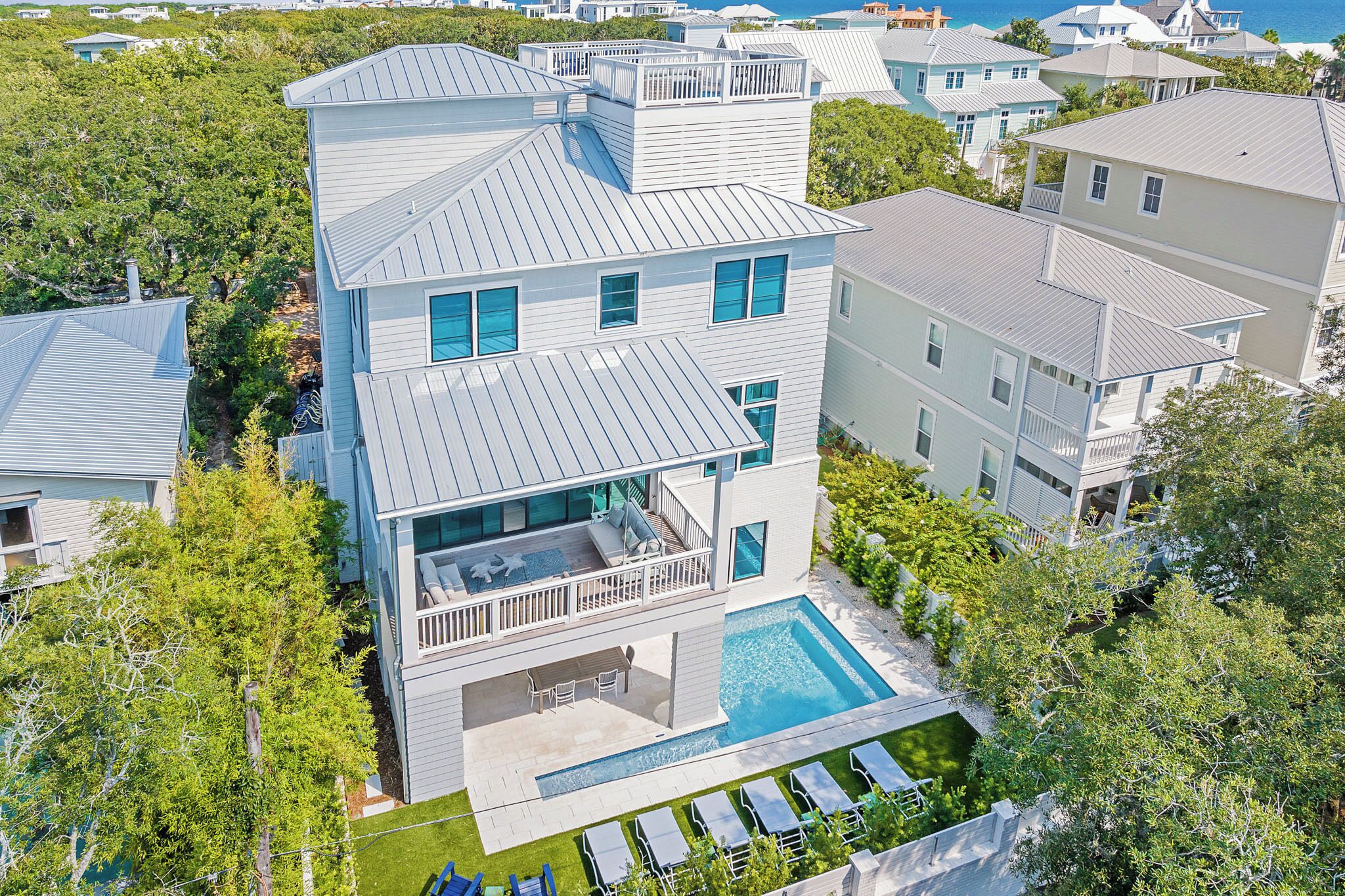 A multi-story house with a swimming pool, large windows, and a balcony.
