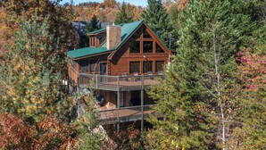 A cabin with a green roof, wooden exterior, and a balcony with railings.