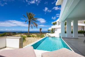 A modern pool area with clear blue water, surrounded by white walls and a view of the ocean. - NEW The Cape at Blue Bay Golf Beach Resort (Sint Michiel)